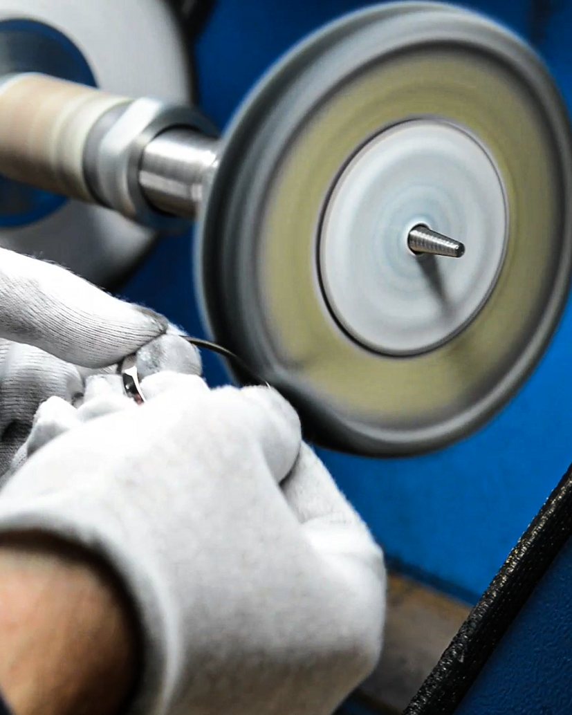 Gloved hands at the polishing wheel in the CLD Design workshop
